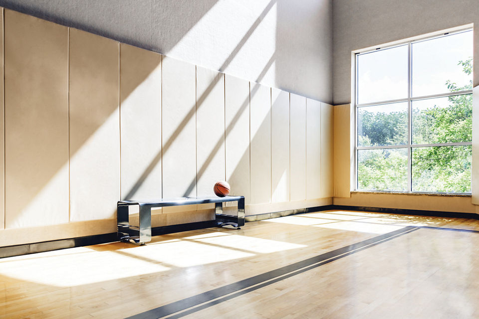 A bench with a basketball on it, in a brightly lit gymnasium