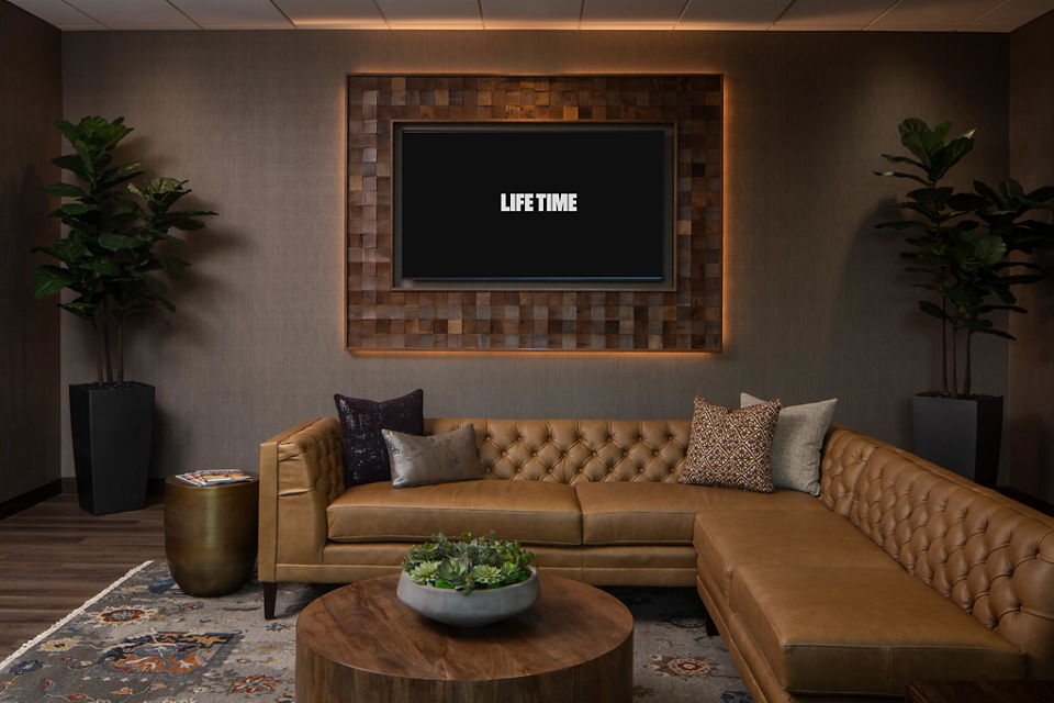 Leather sectional couch in front of a digital screen showing the Life Time logo