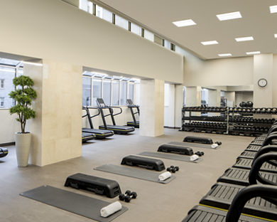 Treadmills, dumbbells and yoga mats laid out in a workout area