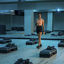 A woman in athletic wear walking through an empty group fitness studio