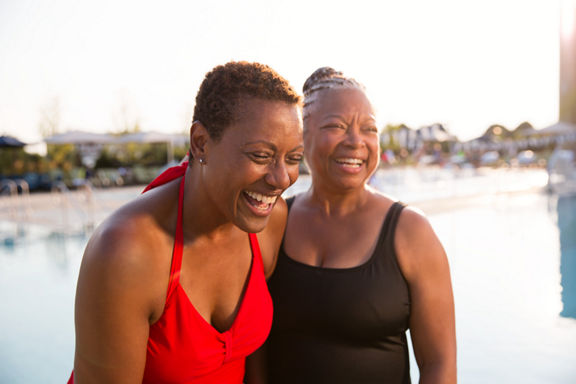 Two women wearing bathing suits standing next to an outdoor pool at Life Time