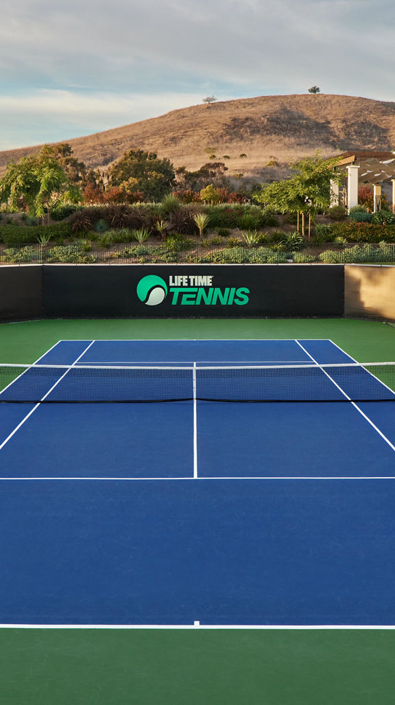 Outdoor tennis court with stadium seating at the Rancho San Clemente Life Time club