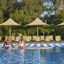 A man and woman smiling at each other while sitting poolside with their feet in the water