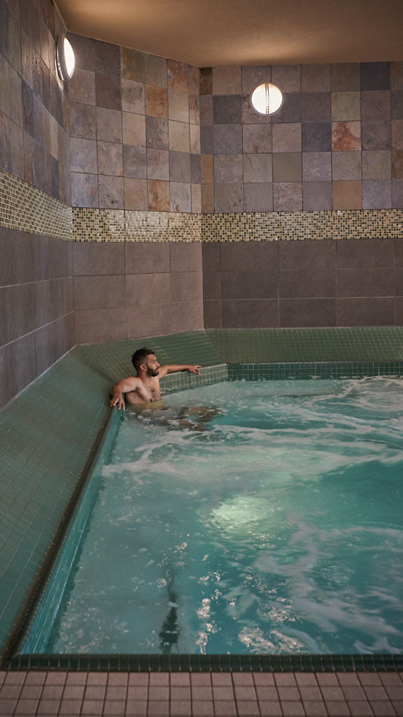 A man sitting and relaxing in an indoor whirlpool at the Life Time South Austin club location