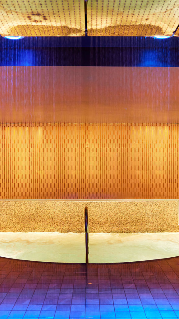 An indoor whirlpool lit with amber tones located in the Life Time Sky club located in New York