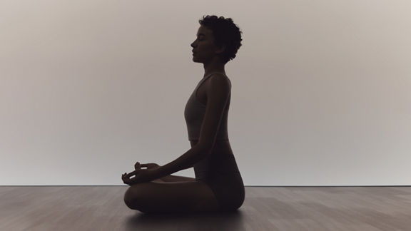 Woman in calm seated sukhasana pose during a surrender yoga class