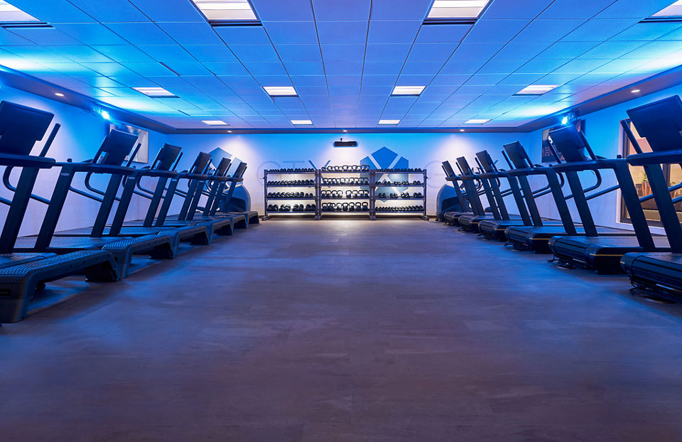 GTX studio filled with treadmills, and hand weights under a blue-toned light